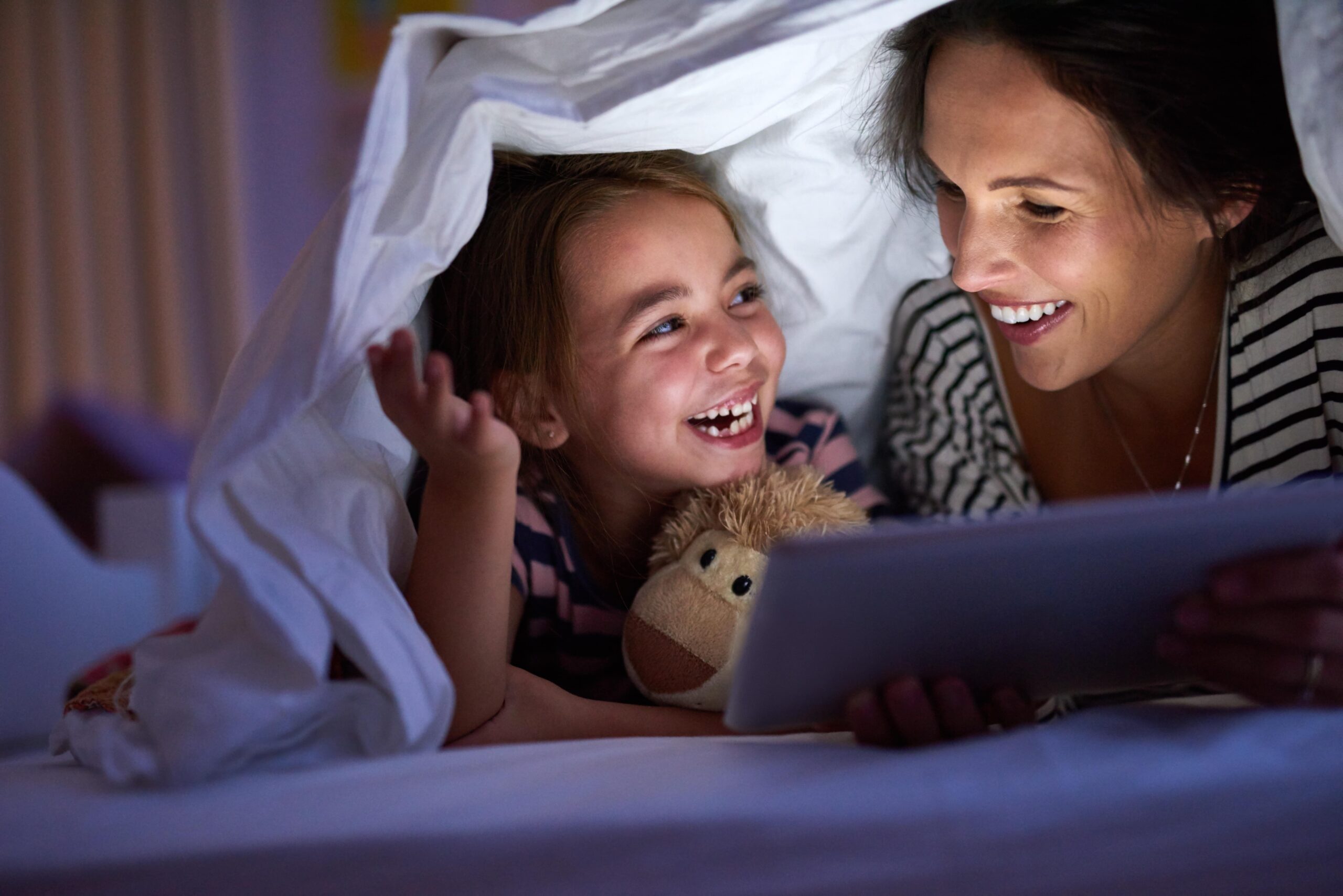 Mom and daughter reading under the covers